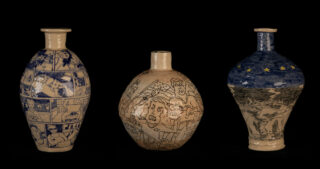 Drei Keramikvasen mit illustrierten Motiven stehen vor einem schwarzen Hintergrund; die linke Vase hat Felder im Comic-Stil, die mittlere zeigt Cartoon-Gesichter und die rechte hat blaue Muster mit gelben Sternen.