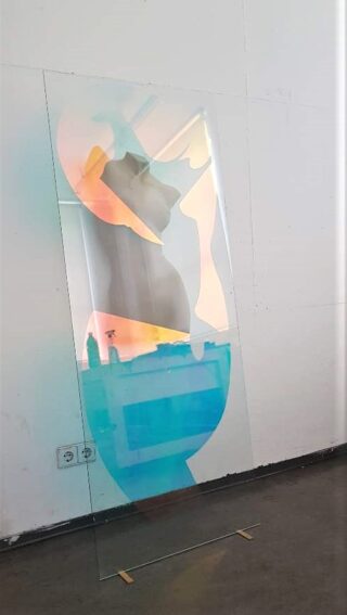 Eine Glasplatte mit abstrakten Formen und bunten Farbverläufen steht aufrecht vor einer weißen Wand in einem minimalistischen Raum.