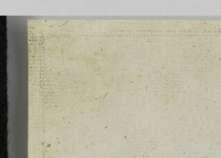 Eine Nahaufnahme eines vergilbten, gealterten Papiers mit schwachen Flecken und Sprenkeln, das links von einem schwarzen und oben von einem weißen Rand eingefasst ist.