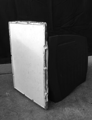 Ein schwarzer CRT-Monitor, dessen Bildschirm entfernt wurde, sodass das Innere sichtbar ist, steht auf einem Betonboden vor einem dunklen Hintergrund.