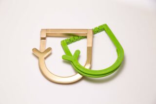 Zwei Taschenrahmen, einer in Gold und einer in Grün, sind überlappend auf einer schlichten weißen Fläche platziert.