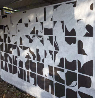 Eine Betonwand ist mit abstrakten geometrischen Formen und Mustern in Schwarz und Weiß bemalt, die in rechteckige Abschnitte unterteilt sind.