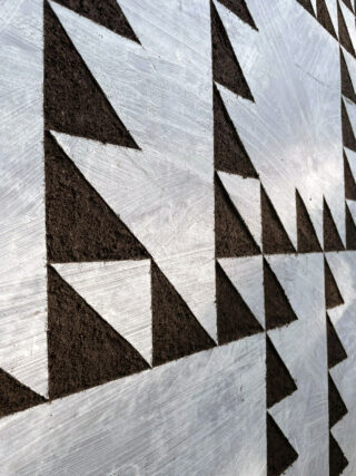 Abstraktes geometrisches Muster mit schwarzen Dreiecken und metallisch-silbernem Hintergrund, das ein sich wiederholendes eckiges Design erzeugt.