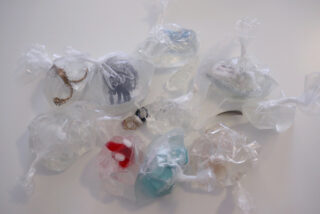 Mehrere kleine Objekte sind einzeln in durchsichtige Plastiktüten verpackt und auf einer weißen Fläche angeordnet.