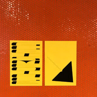 Zwei gelbe Poster mit abstrakten schwarzen Motiven auf einer orangefarbenen, sechseckig gefliesten Wand. Das linke Poster zeigt horizontale Formen, das rechte ein Dreieck mit abgestuftem Rand.