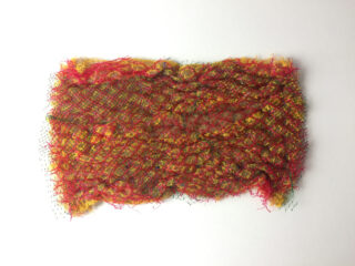 Auf einem weißen Hintergrund befindet sich ein rechteckiges Stück rotes, gelbes und grünes Maschennetz mit einer rauen Textur.