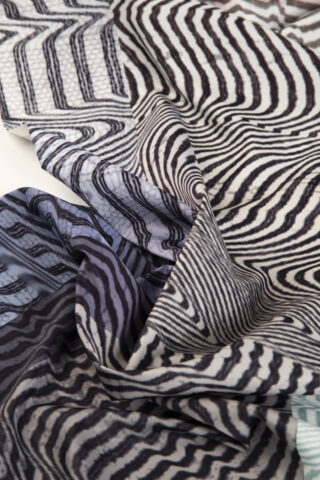 Eine Nahaufnahme eines zerknitterten Stoffes mit schwarz-weißen Wellen- und Zickzack-Streifenmustern.