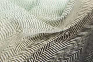 Nahaufnahme eines Stoffes mit wellenförmigen, parallelen schwarzen und weißen Linien, die ein optisches Täuschungsmuster erzeugen, dargestellt mit Falten und Drapierungen.