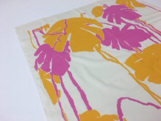 Ein Stück weißer Stoff mit einem kräftigen, abstrakten Aufdruck mit großen orangefarbenen und rosa tropischen Blättern und Stängeln.