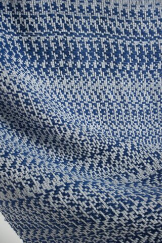 Nahaufnahme eines blau-weißen Webstoffs mit einem geometrischen, sich wiederholenden Muster mit diagonalen und horizontalen Linien.