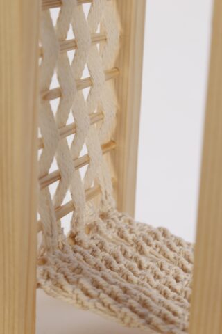 Nahaufnahme eines Holzstuhls mit geflochtener Sitzfläche und einer Rückenlehne aus ineinander verschlungenen hellen Seilen.