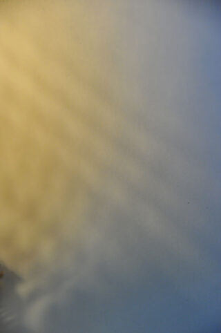 Weiche, abgestufte Lichtmuster mit Gelbtönen auf der linken Seite, die in Blau auf der rechten Seite übergehen, wodurch ein glatter und abstrakter Hintergrund entsteht.