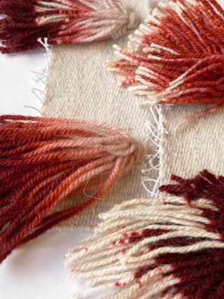 Weiß-roter Wollteppich mit Fransen.