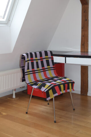 Stoff mit geometrischen Mustern über einen Stuhl gelegt.