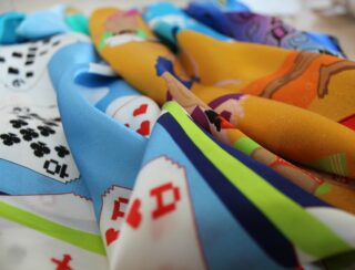 Eine Nahaufnahme von buntem Stoff mit aufgedruckten Spielkarten und Comicfiguren in verschiedenen Posen.