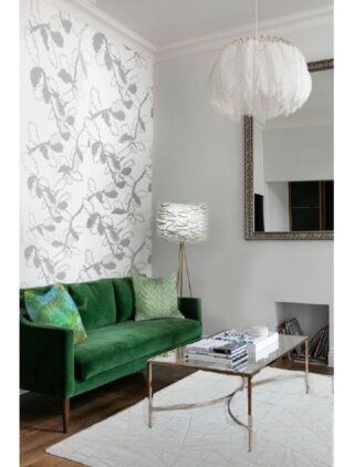 Ein modernes Wohnzimmer mit einem grünen Samtsofa, einem Couchtisch aus Glas, einem weißen Strukturteppich, einer Blatttapete und einer Hängelampe mit Federn. Über dem Kamin hängt ein großer Spiegel.