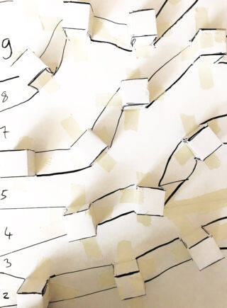 Ein handgezeichnetes Diagramm mit nummerierten Reihen und miteinander verbundenen Pfaden mithilfe von aufgeklebten Papierrechtecken und schwarzen Linien auf weißem Hintergrund.