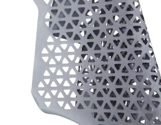 Nahaufnahme eines grauen Materials mit einem sich wiederholenden dreieckigen Ausschnittmuster, möglicherweise Teil eines Stuhls oder einer Strukturplatte.