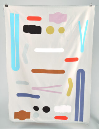Ein weißer Stoff mit bunten geometrischen Formen, darunter Rechtecke, Kreise und Linien in Blau, Rot, Gelb, Schwarz, Braun, Lila und Grau, die in einem verstreuten Muster angeordnet sind.