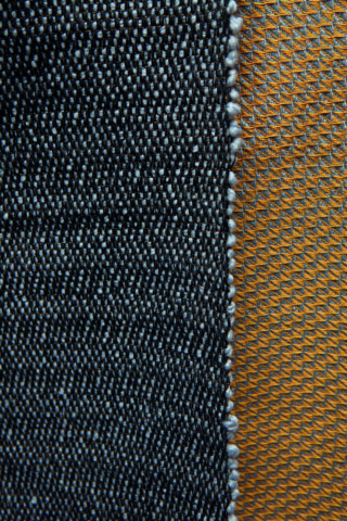 Nahaufnahme zweier kontrastierender Textilmuster: ein dichter dunkelblauer Webstoff links und ein lockerer gelber Netzstoff rechts, getrennt durch eine sichtbare Naht.