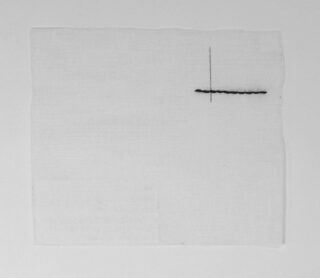Ein quadratisches Stück weißen Stoffes mit einer schwarzen horizontalen Stepplinie, die im oberen rechten Bereich von einer kurzen vertikalen Linie durchschnitten wird.