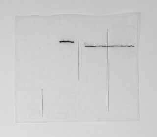 Auf einem Stück weißen Stoff sind fünf dünne, gerade schwarze Linien in unterschiedlicher Länge und Ausrichtung zu sehen, wobei sich oben rechts zwei Linien kreuzen.