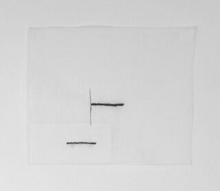 Ein weißer quadratischer Stoff mit zwei schwarzen Nählinien, eine horizontale und eine vertikale, die sich in der Nähe der Mitte kreuzen, sowie einer weiteren horizontalen Linie auf einem kleineren angefügten Quadrat unten links.