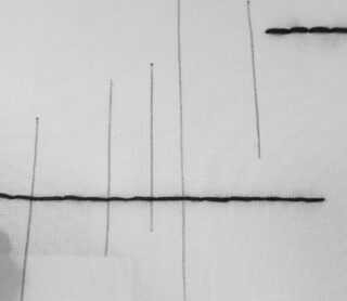 Schwarze Linien, sowohl vertikale als auch horizontale, sind in einem minimalen, geometrischen Muster auf einen weißen Stoffhintergrund gestickt.