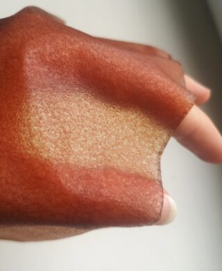 Eine Hand mit einer dünnen, durchscheinenden Schicht aus braunem Fruchtleder über den Fingern.