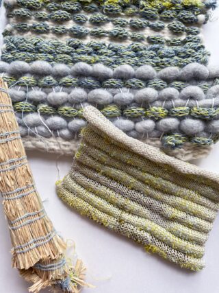 Ein gewebter Stoff mit dicken, grauen und grünen Strukturgarnen, ein kleineres Strickmuster in hellen Farben und ein mit Faden umwickeltes Strohbündel auf einer weißen Oberfläche.