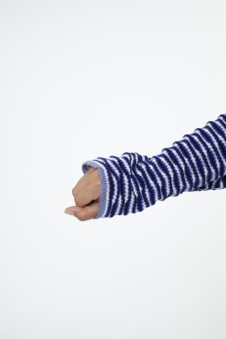 Eine Hand, die einen langärmeligen, blau-weiß gestreiften Pullover trägt, ist vor einem schlichten weißen Hintergrund teilweise zur Faust geballt.