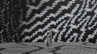 Ein vertikales Objekt mit einem schwarz-weißen Zickzack-Muster steht auf einer Oberfläche mit passenden Mustern vor einem ähnlich gemusterten Hintergrund.