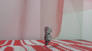 Ein zerknittertes Stück schwarz-weißes Netz steht aufrecht auf einer rot gemusterten Oberfläche, im Hintergrund ein rot-weiß gestreifter Hintergrund.