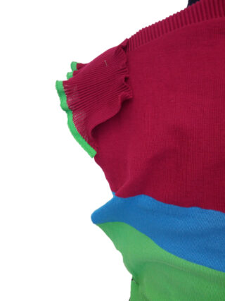 Nahaufnahme eines ärmellosen Oberteils mit roten, blauen und grünen gerippten Stoffabschnitten und einem kleinen Rüschendetail an der Schulter.