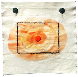 Ein Stück Stoff mit zwei grünen Kreisen oben, einem schwarz umrandeten Rechteck und einem orangefarbenen kreisförmigen Muster mit einer strukturierten Mitte innerhalb des Rechtecks.