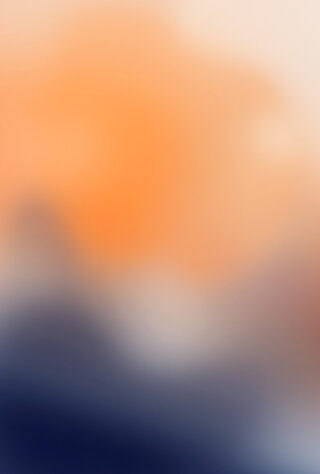Abstraktes, unscharfes Bild mit dominanten Orangetönen oben und Dunkelblau unten, wodurch ein Farbverlaufseffekt entsteht. Es sind keine klaren Formen oder Objekte sichtbar.