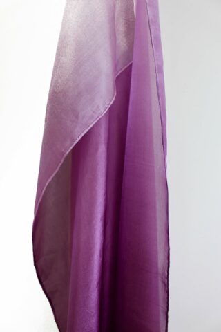 Eine Nahaufnahme eines halbtransparenten, violetten Stoffes, der vor einem hellen Hintergrund drapiert ist.