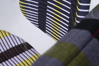 Nahaufnahme eines Stoffes mit horizontalen Streifen in Gelb, Weiß und Schwarz und einem strukturierten Rippenmuster.