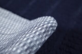 Nahaufnahme eines gefalteten Stücks strukturierten Stoffes mit einem blau-weißen Webmuster.