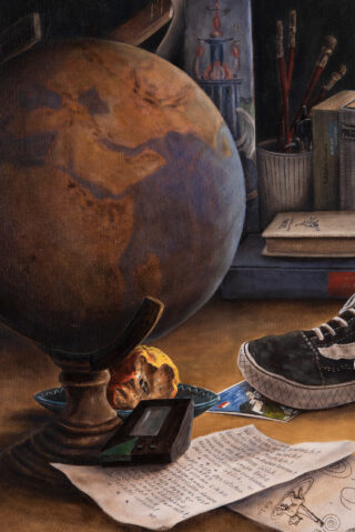 Ein Schreibtisch mit einem Globus, einem Turnschuh, einem digitalen Gerät, Papieren mit Zeichnungen und Schriften, einem halb aufgegessenen Apfel, Büchern, Fotos und einem Becher mit Bleistiften.