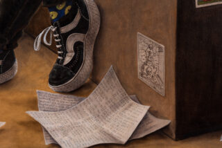 Eine Nahaufnahme eines schwarz-weißen Sneakers, handgeschriebene Blätter mit Zahlen und Text auf dem Boden und eine auf eine braune Oberfläche geklebte Zeichnung.