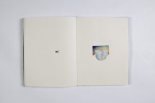 Ein offenes Buch mit einem kleinen Foto auf der linken Seite und einem größeren, abstrakten Bild mit einem Eisberg auf der rechten Seite, beide vor einem leeren Hintergrund.