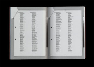 Ein offenes Buch mit zwei Seiten, in denen alphabetische Wortlisten getippt sind. Jede Seite wird von weißen Ecklaschen gehalten und hat auf der linken Seite zwei Löcher.