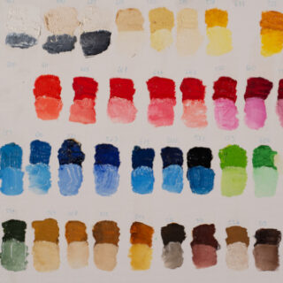 Eine Tabelle mit in Reihen angeordneten Farbmustern, die eine Palette neutraler, roter, blauer, grüner und brauner Farbtöne auf weißem Hintergrund zeigt.