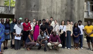 Ein Gruppenfoto von Studierenden vor einer Betonwand.