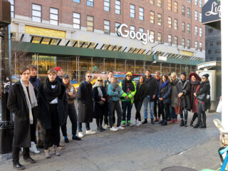 Eine Gruppe von Menschen steht auf einem Bürgersteig vor einem Gebäude mit einem großen Google-Schild und einem Gerüst.