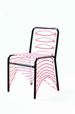 Ein Stuhlrahmen aus Metall, über dessen Sitzfläche und Rückenlehne ein roter Faden oder Draht gespannt ist, der geometrische Muster bildet.