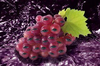 Eine Traube roter Weintrauben mit grünem Blatt, jede Traube zeigt ein realistisches menschliches Auge, vor einem zerknitterten violetten Folienhintergrund.