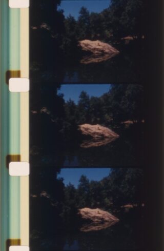 Ein Filmstreifen mit drei Bildern, der einen großen Felsen zeigt, der von Bäumen umgeben ist und sich in einer Wassermasse unter blauem Himmel spiegelt.