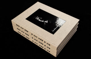 Ein Stapel aus drei beigefarbenen, in Leinen gebundenen Büchern mit einem Schwarzweißporträt einer Person in Uniform auf dem Einband vor einem schwarzen Hintergrund.